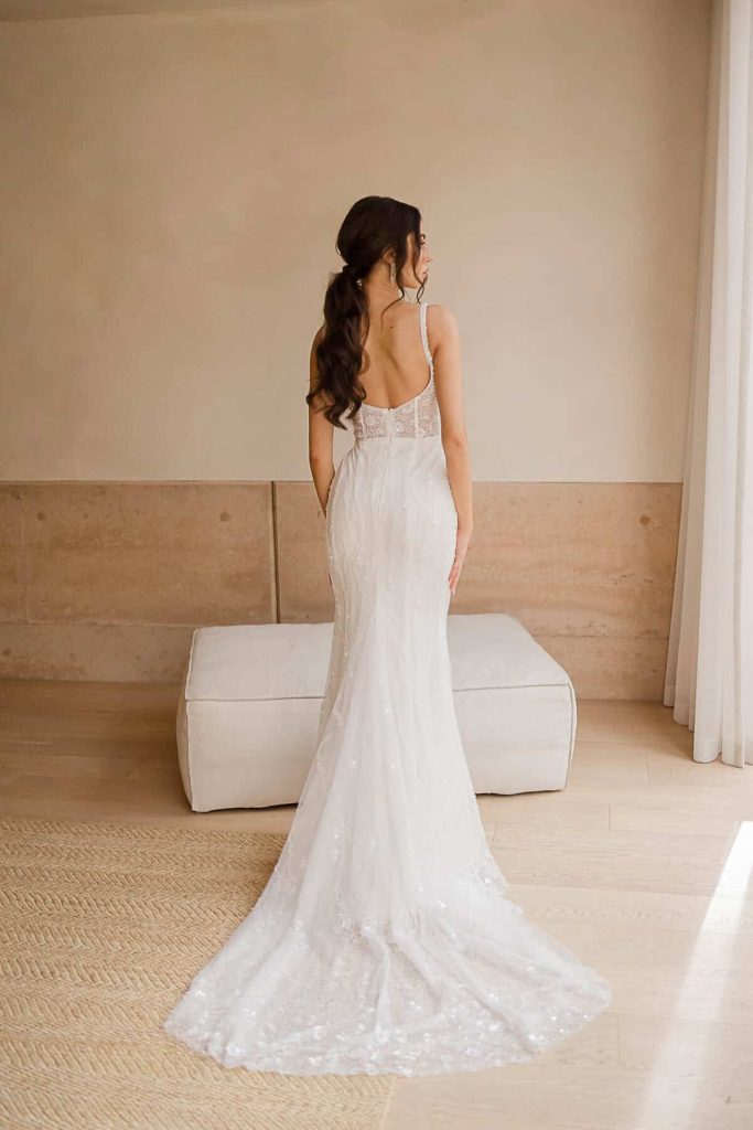 Low scoop back beaded sheath wedding gown with train by Elysian Bridal