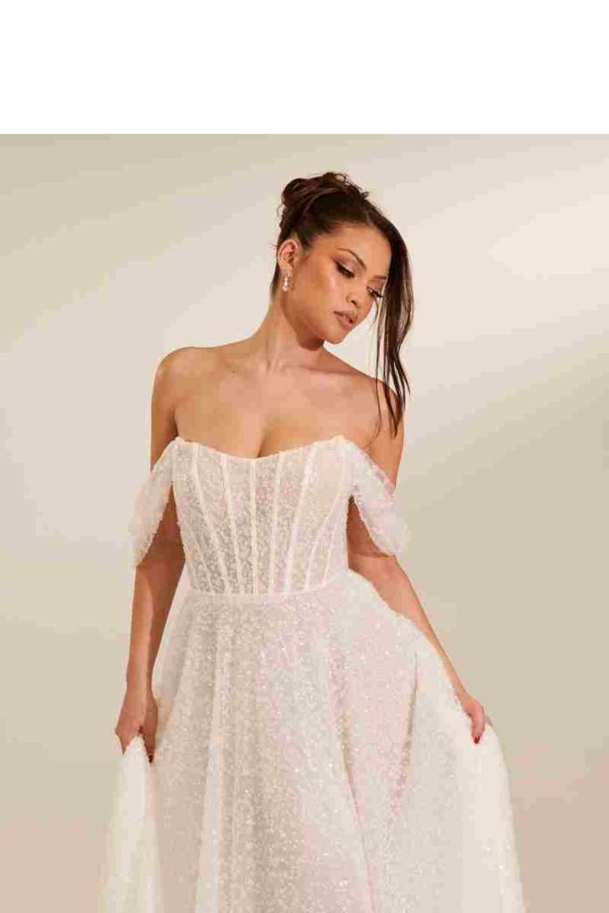 Off-the-shoulder glitter tulle gown with sheer boned bodice by Zavana Bridal